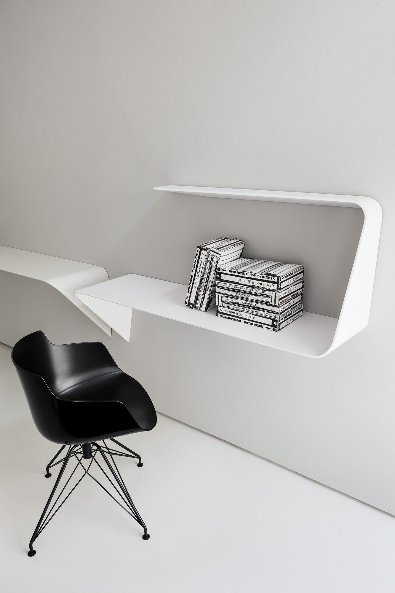 Weißer Mamba Wandsekretär von MDF Italia mit Büchern und schwarzem Stuhl im minimalistischen Design.