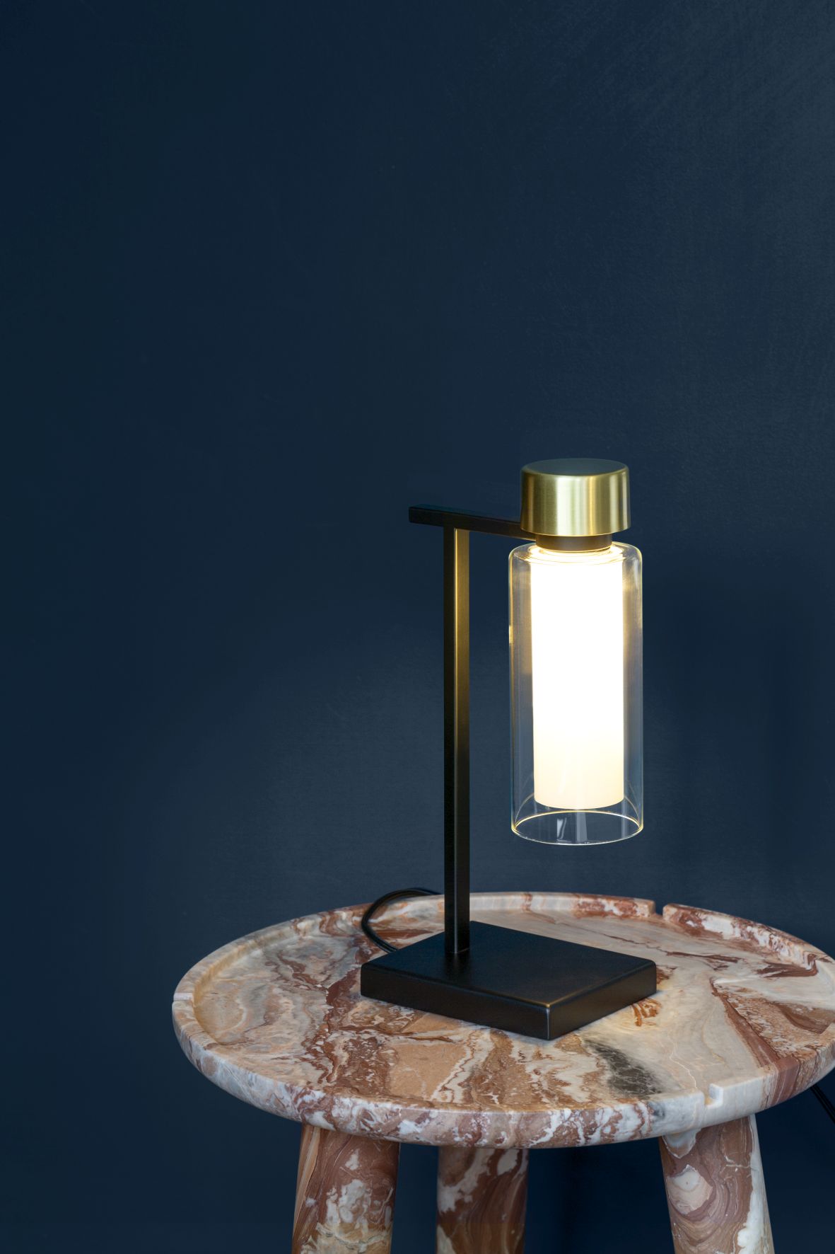 Osman Tischleuchte von Tooy: Moderne Lampe mit Glaszylinder und goldenem Akzent auf Marmortisch.