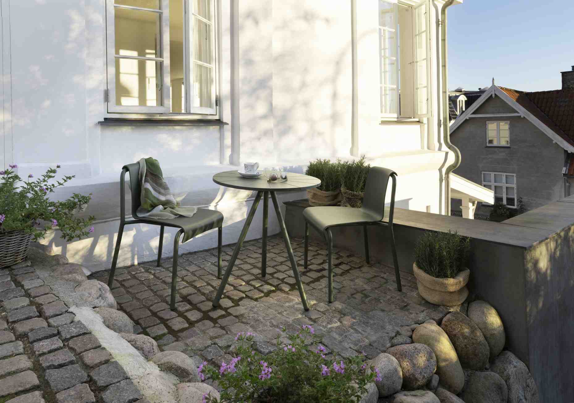 Grüne Nami Dining Chair Outdoor Stühle von Houe mit Tisch auf einer Terrasse.