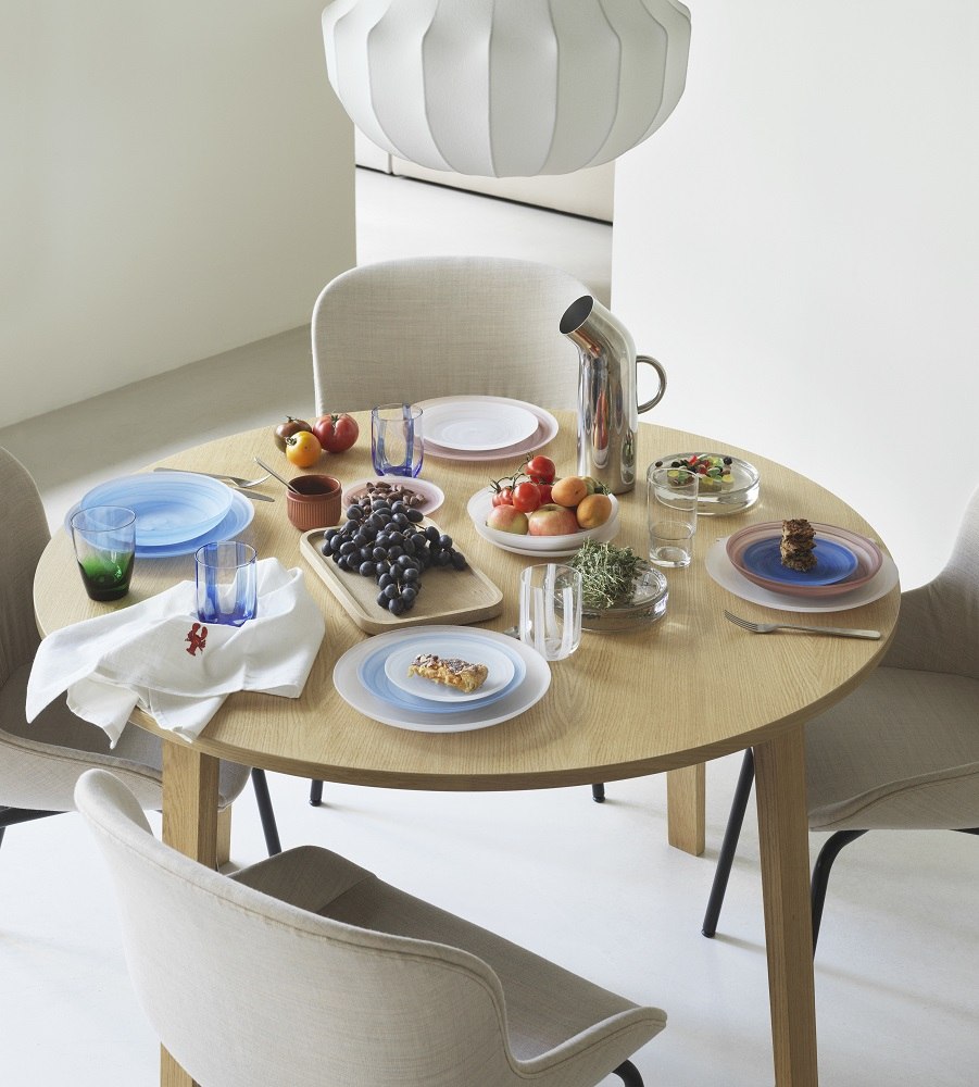 Esstisch gedeckt mit Edelstahl Krug und farbigen Gläsern, Normann Copenhagen Design.