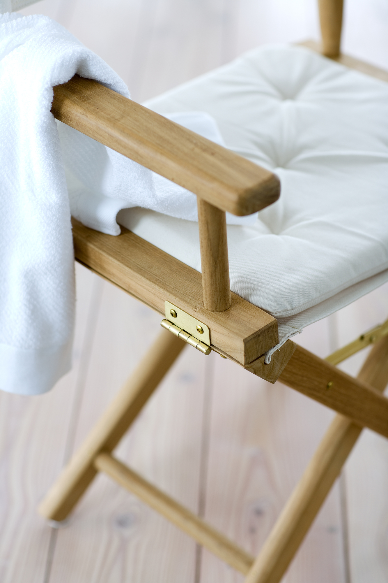 Detailaufnahme des Skagerak Director's Chair Stuhls mit weißem Sitzkissen und Handtuch, geeignet für Indoor und Outdoor.