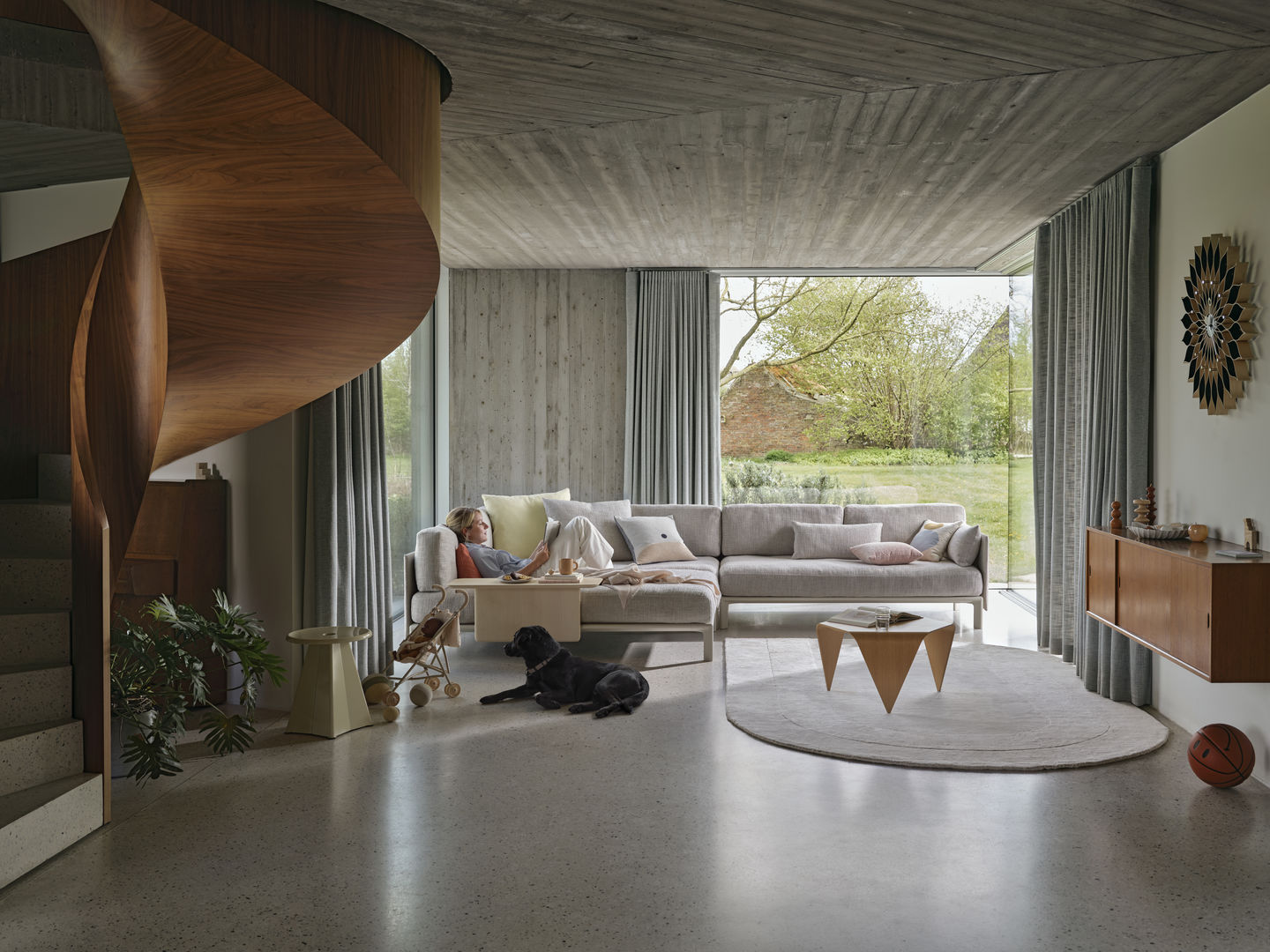 Wohnzimmer mit Vitra Anagram Panel (90 cm), Sofa, Teppich und Holztreppe in modernem Design.