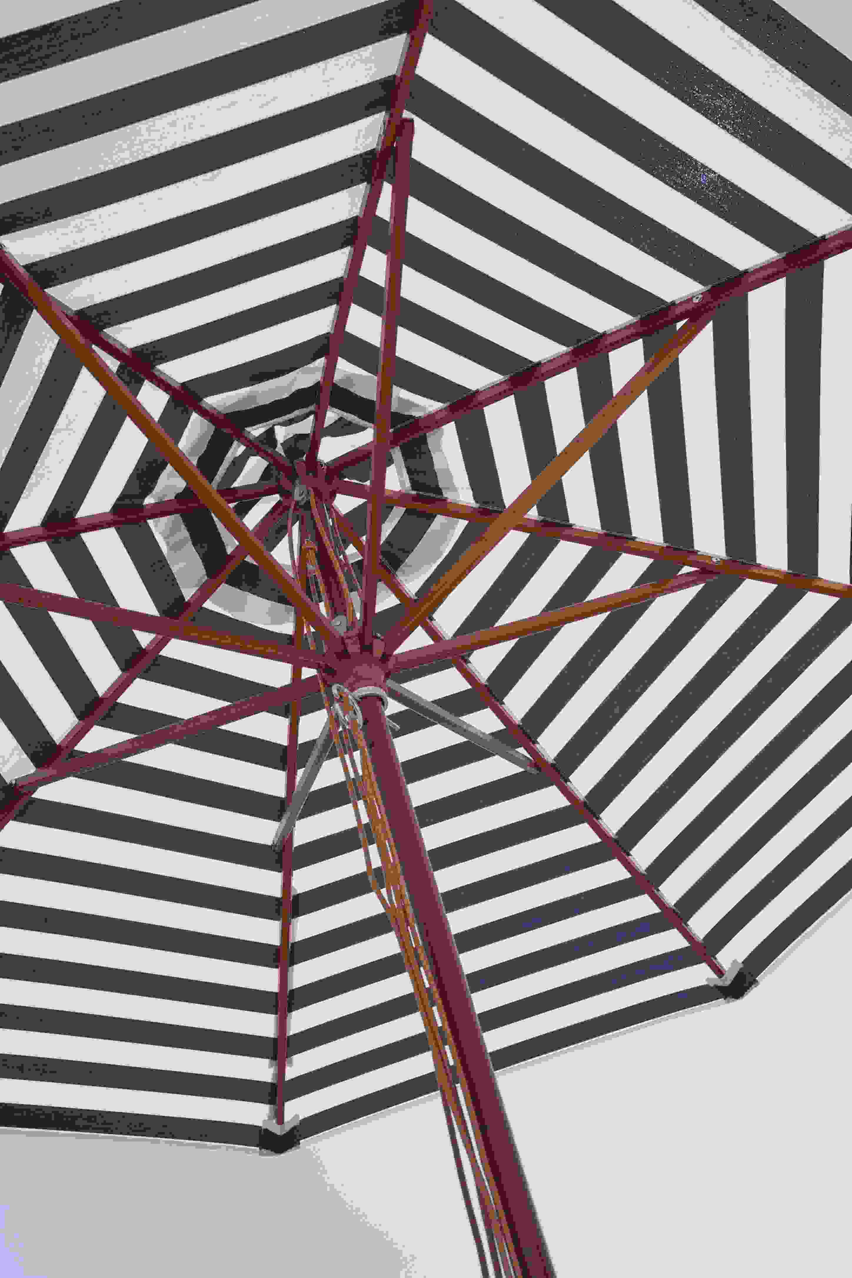 Detailaufnahme des Messina Sonnenschirms von Skagerak mit off-white Streifen und rotem Gestell.