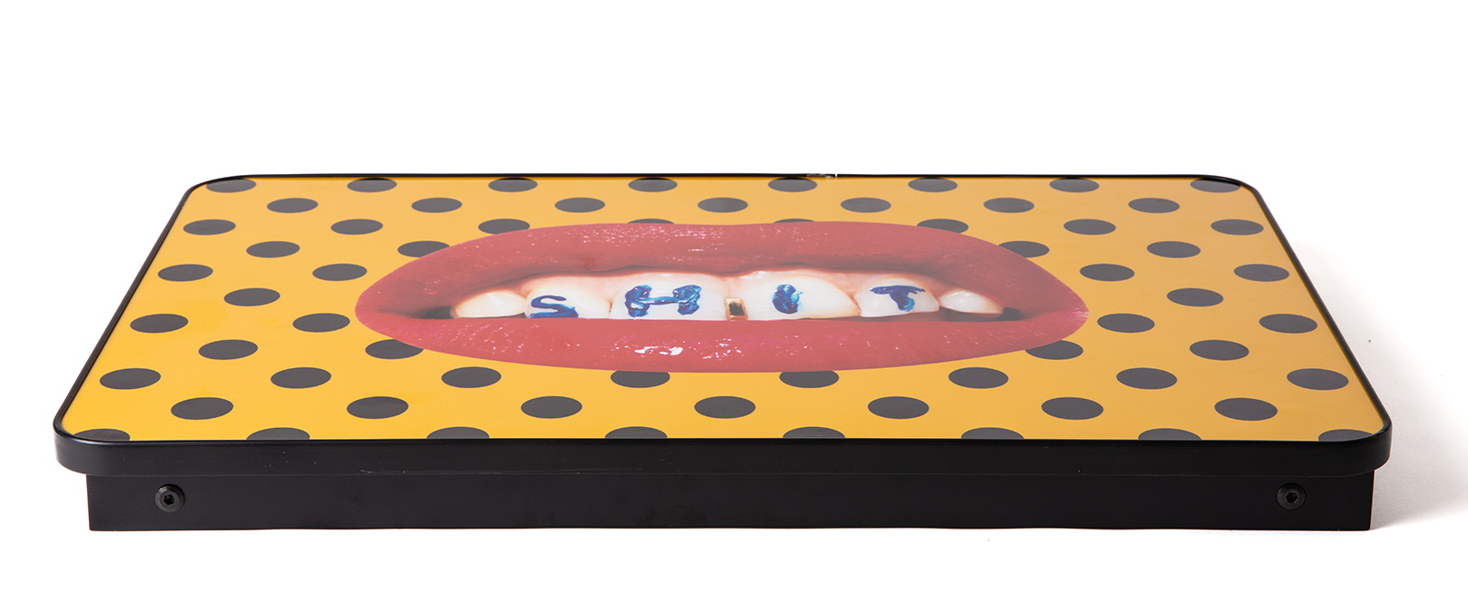 Toiletpaper Seletti Sofa Tray: Klappbares Tablett mit gelbem Punktmuster und rotem Mund mit "Shit"-Zahnschrift.