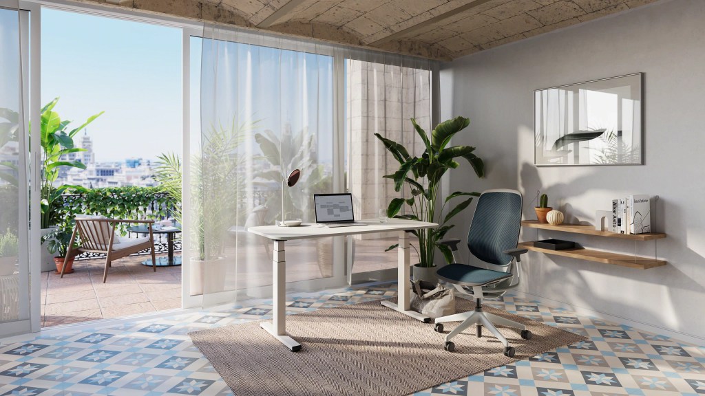 Büro mit Steelcase Karman Bürodrehstuhl, höhenverstellbarem Schreibtisch und Blick auf eine sonnige Terrasse.