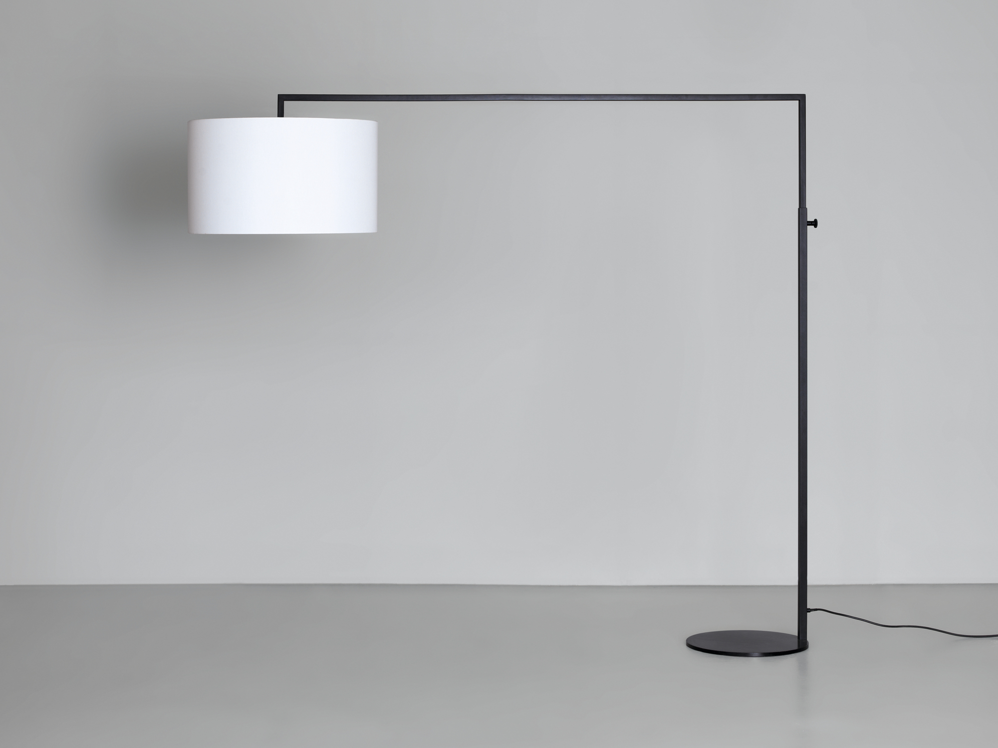 High Noon Stehleuchte in Weiß: Moderne Stehlampe mit zylindrischem Lampenschirm und schwarzem Gestell.