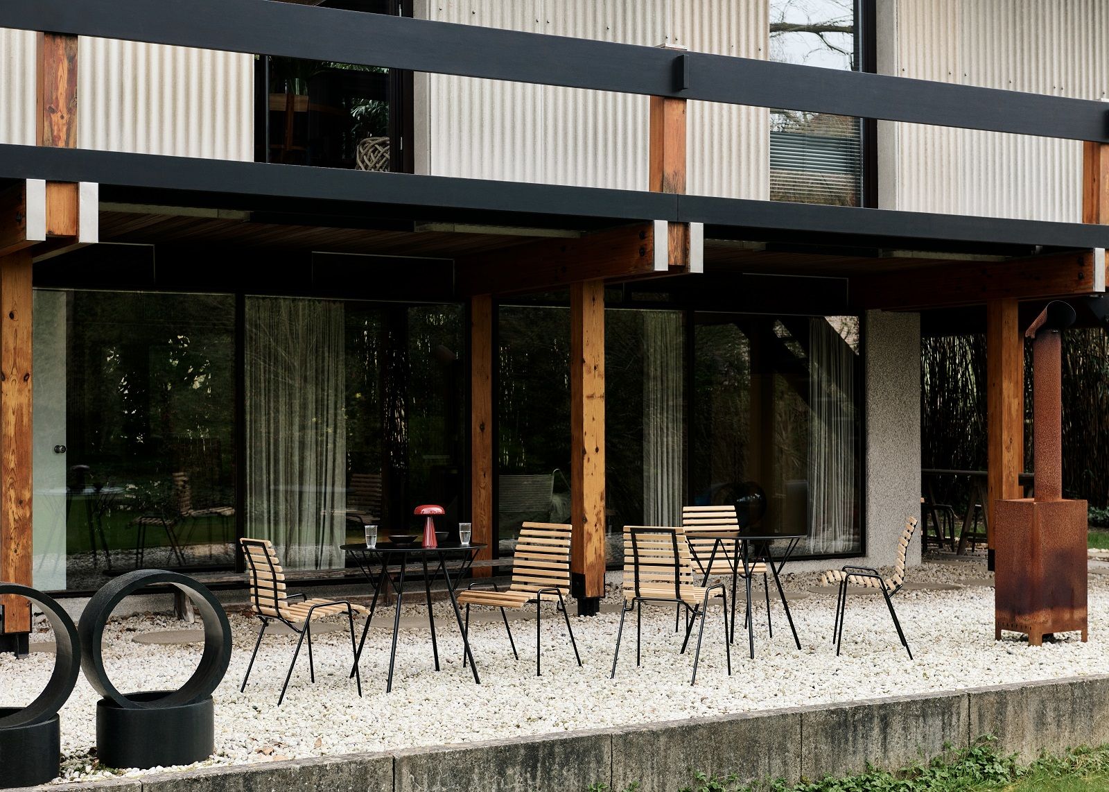 RFH Robin Day Esstisch von AndTradition im Außenbereich mit Stühlen auf Kiesboden.