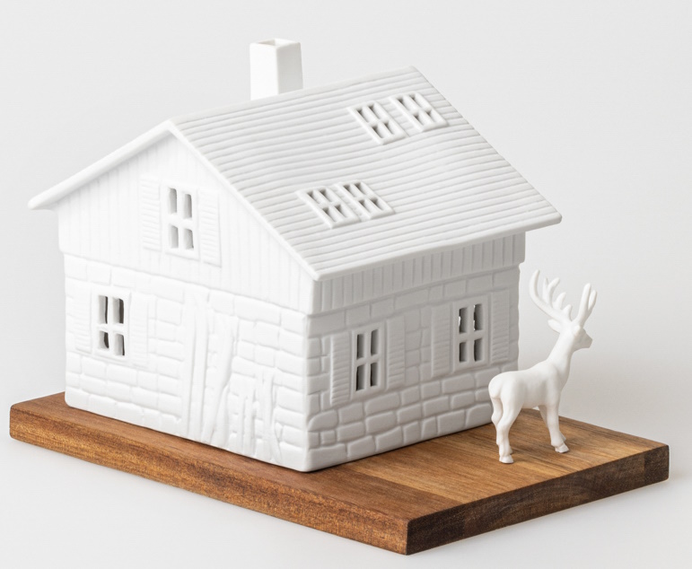 Weißes Lichthaus Skihütte von Räder auf Holzsockel mit kleinem weißen Hirsch als Dekoration.