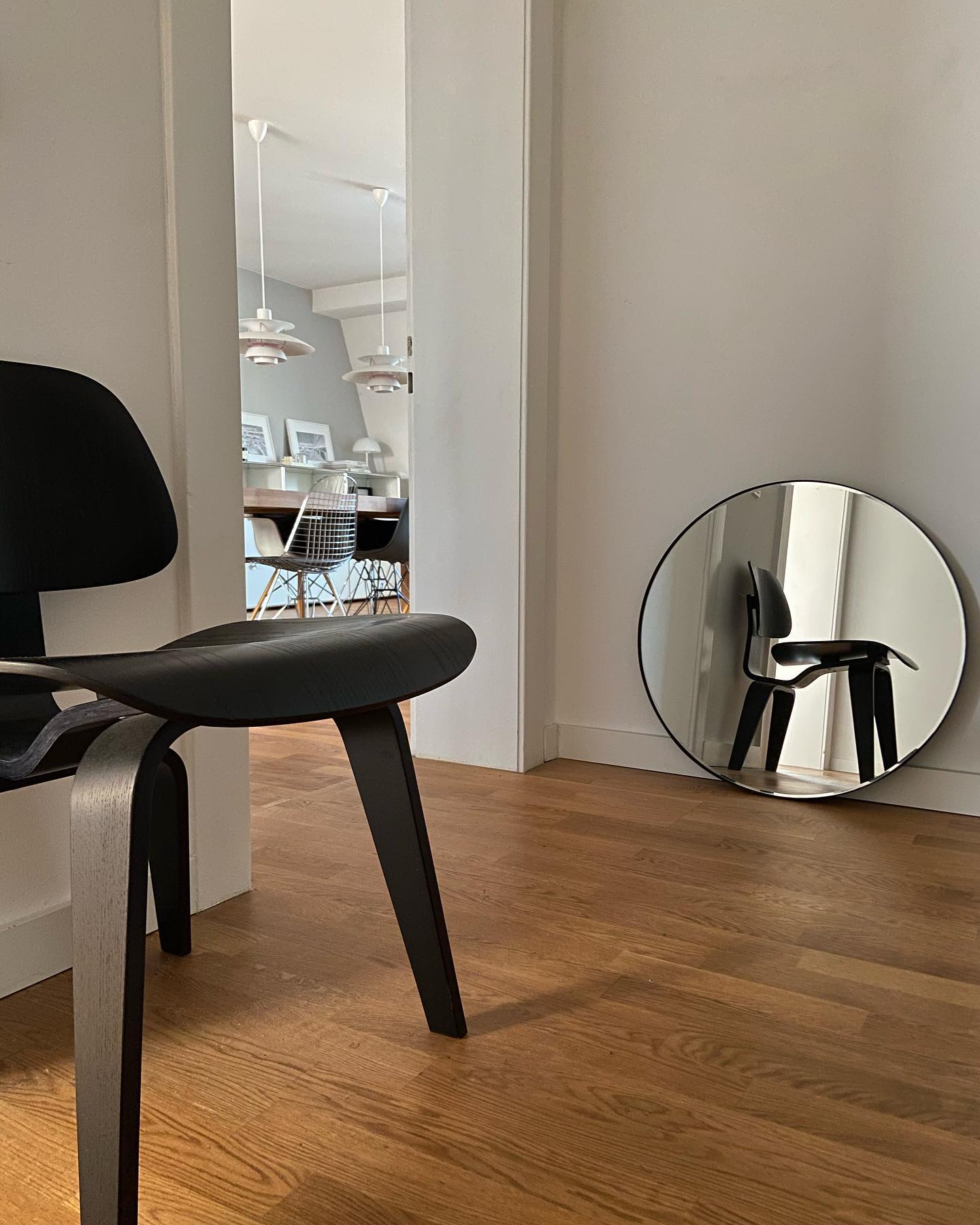 Schwarzer Holzstuhl, Plywood Group Designstuhl von Vitra, vor Spiegel auf Holzboden.