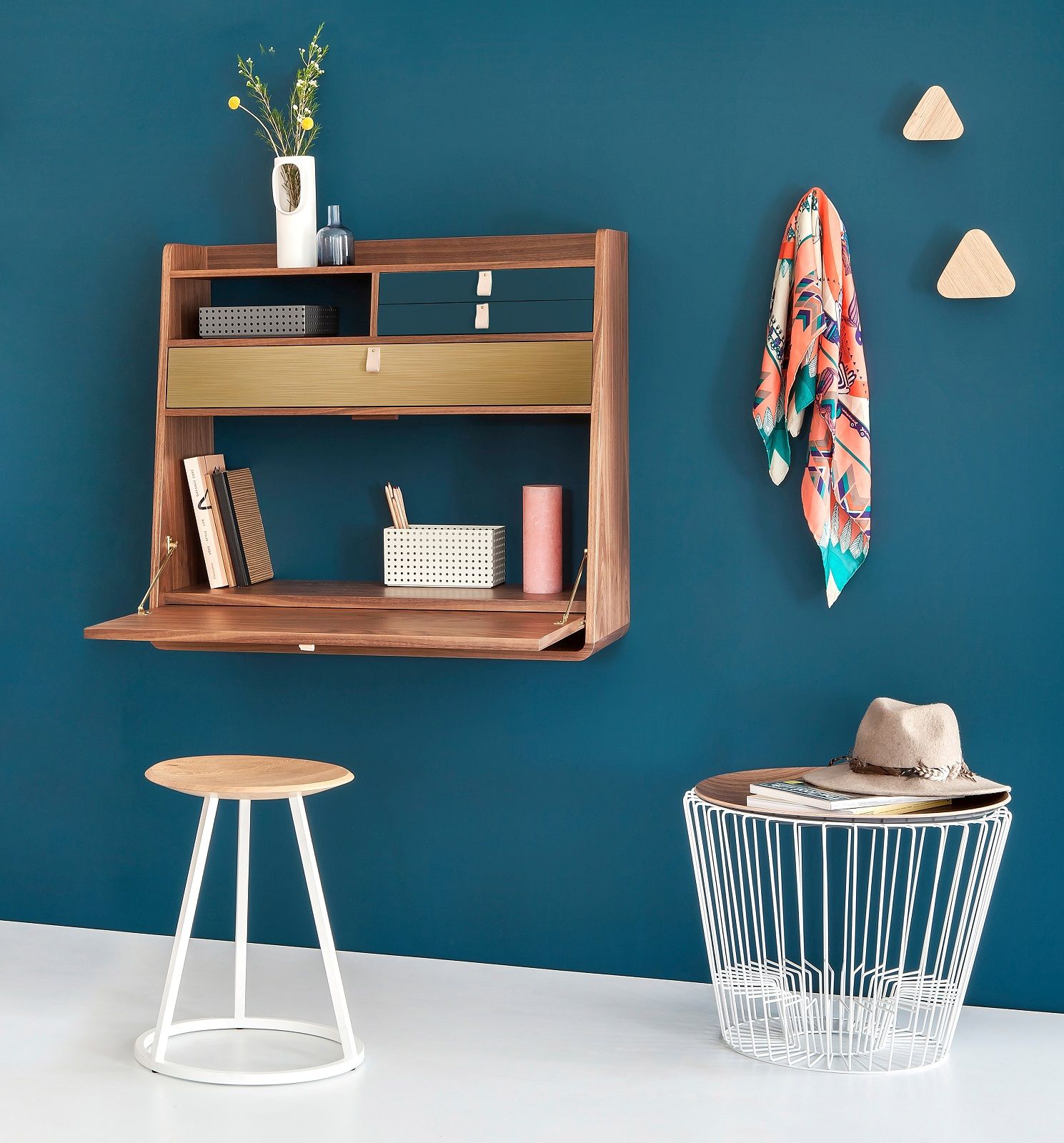 Gaston Wandsekretär aus Walnuss und Petrolblau an blauer Wand, mit Hocker und Beistelltisch.