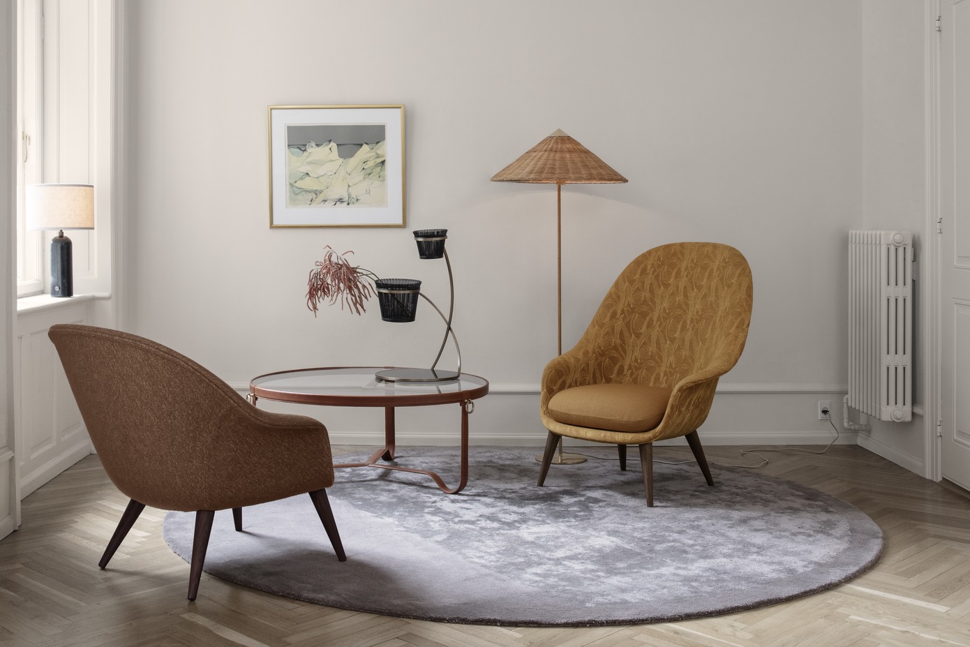 Wohnzimmer-Szene mit Gubi Adnet Couchtisch, Sesseln, Stehlampe und Teppich auf einem Holzboden.