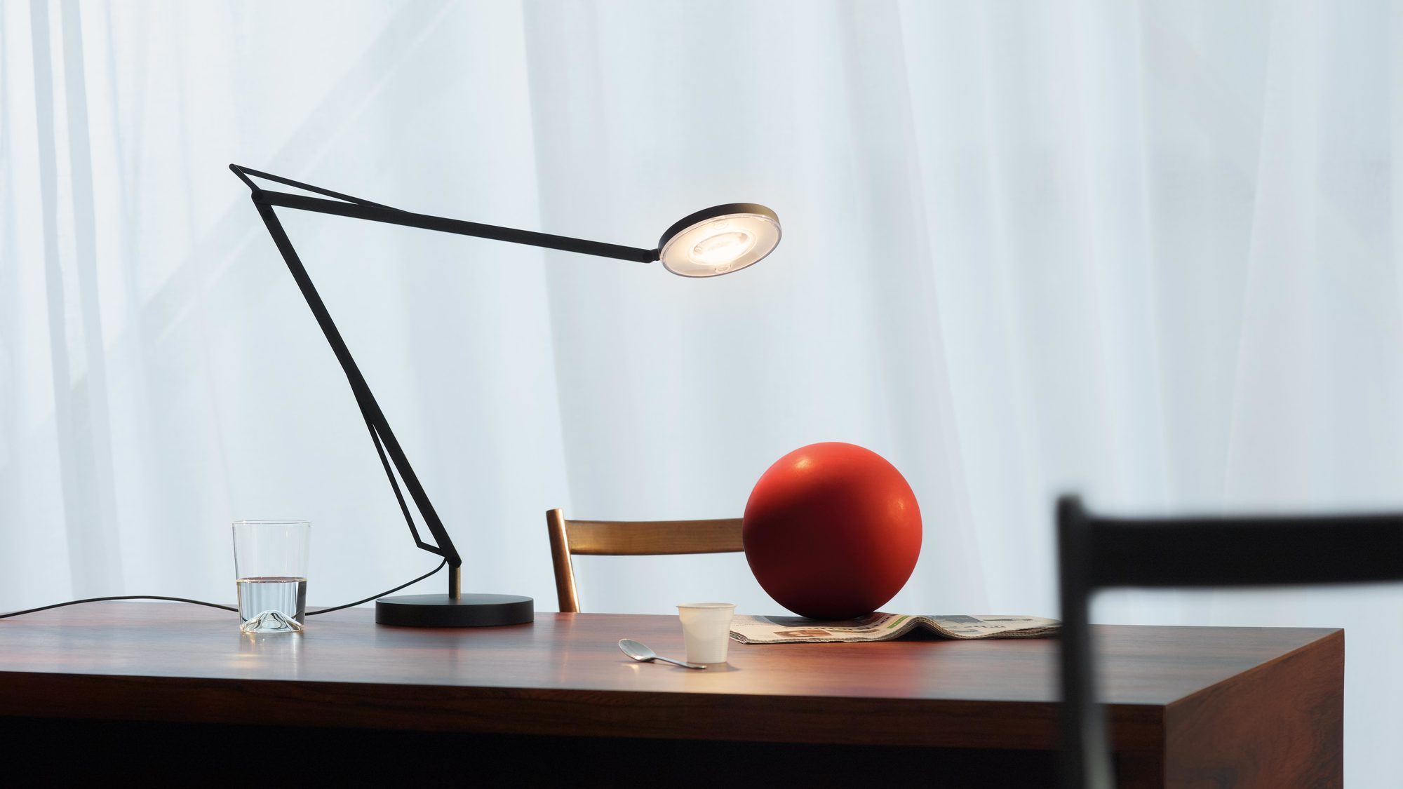 Graue John Tischleuchte auf dunklem Schreibtisch, modernes Design für Büro und Arbeitszimmer.