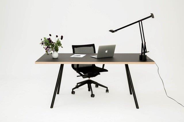 Schwarzer Schreibtisch mit Stahlgestell von New Tendency, Laptop, Lampe und Bürostuhl vor weißem Hintergrund.