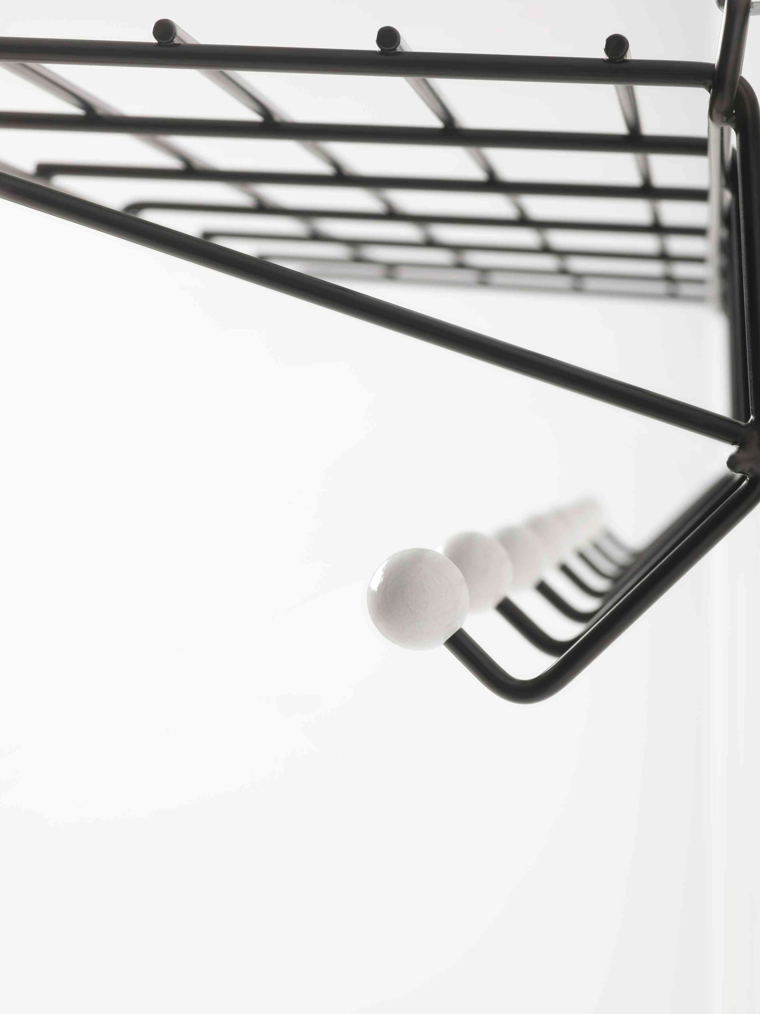 Detailaufnahme der DZ 05 Garderobe Spectrum: Schwarzes Metallgestell mit weißen Knaufhaken und Ablagegitter.