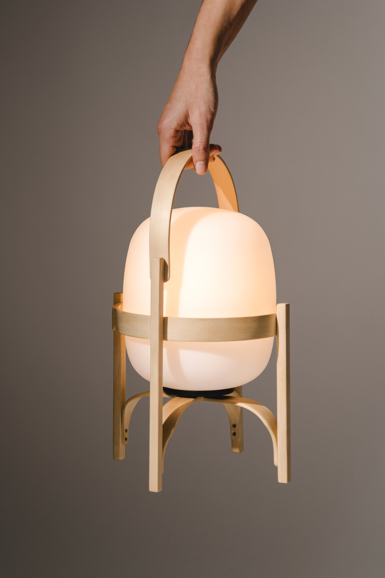 Hand hält Cestita Tischleuchte mit Opal Kunststoffschirm, moderne Tischlaterne für stimmungsvolle Beleuchtung.