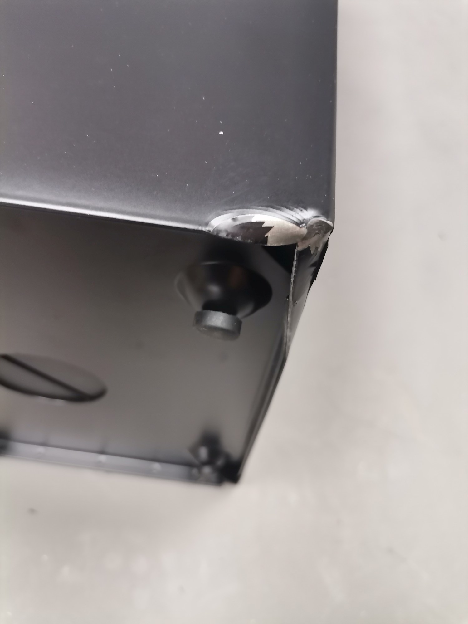 Detailaufnahme: Beschädigung an der Ecke des schwarzen Via Schirmständers, ein Mängelexemplar mit Lackschäden.