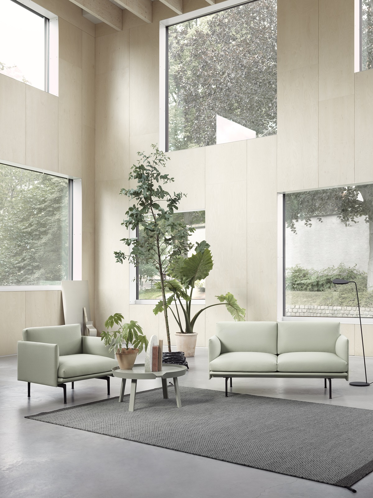 Helles Wohnzimmer mit Muuto Outline Sofa und Sessel in Mintgrün auf grauem Teppich.
