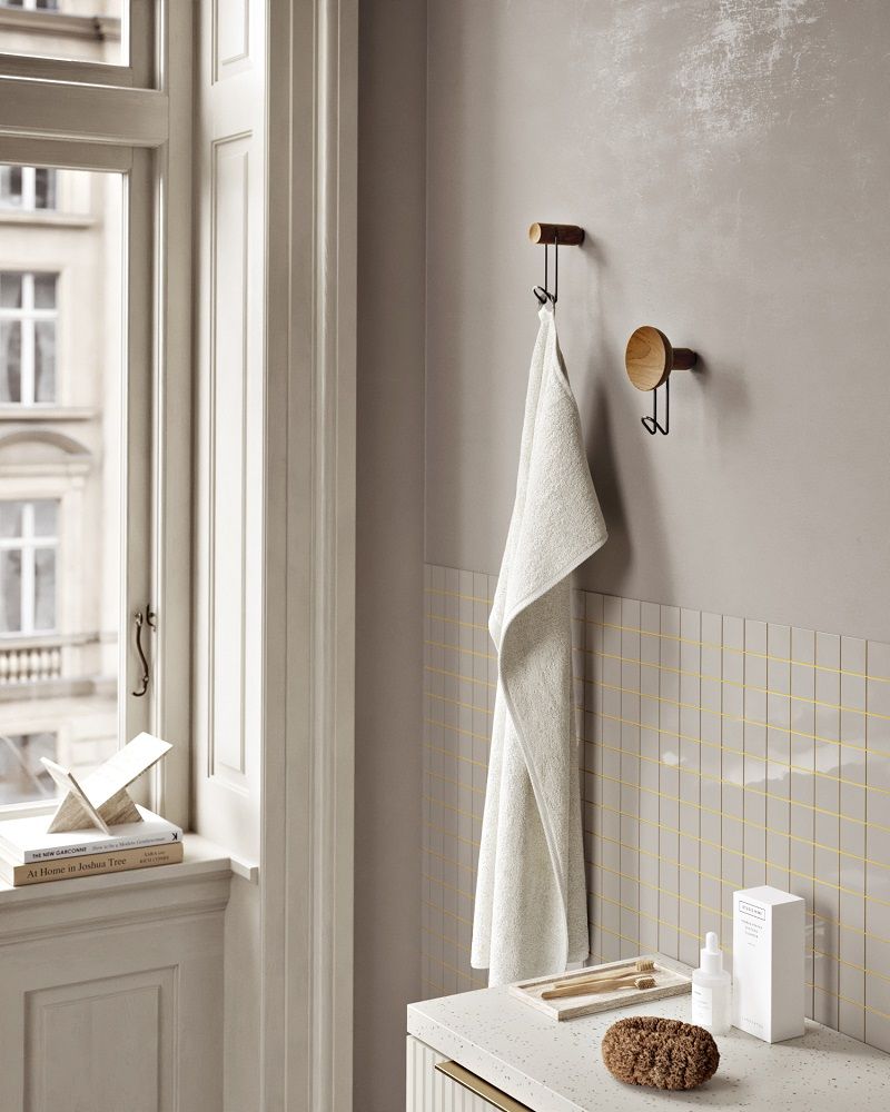 Badezimmer-Szene mit Handtuchhalter aus Holz, möglicherweise ein Woud Zeitschriftenhalter, und Bad-Accessoires.