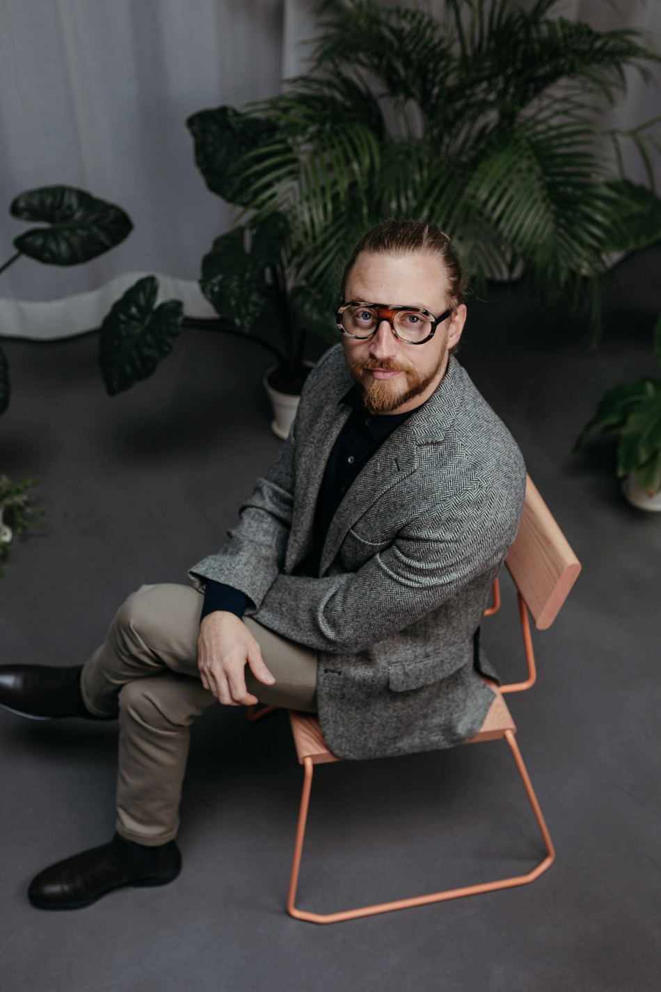 Mann sitzt auf D:005 Stuhl Fuchs & Habicht. Moderner Holzstuhl mit Metallgestell. Designmöbel für Wohnen und Büro.