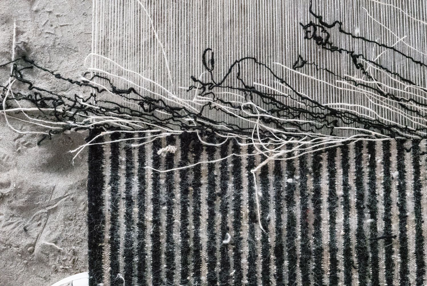 Detailaufnahme des Nanimarquina Blur Teppichs: Handgefertigter Wollteppich mit abstraktem, verschwommenem Muster in Schwarz und Weiß.