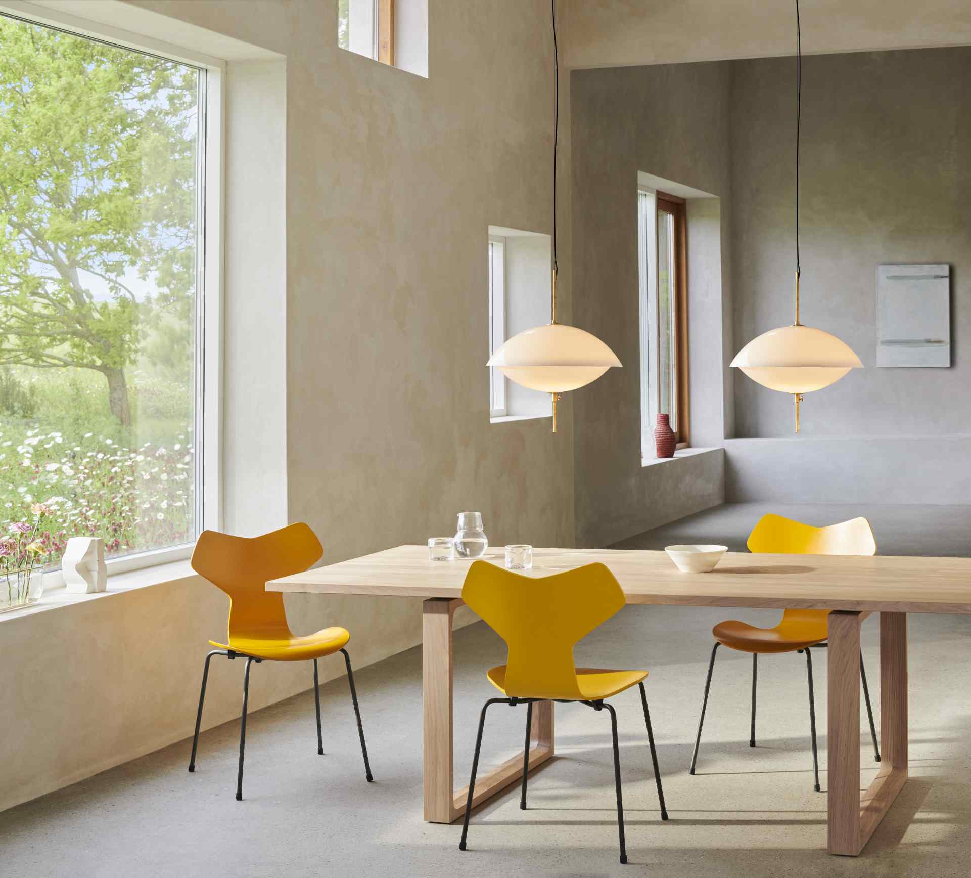 Esszimmer mit Fritz Hansen Clam Pendelleuchten, Design-Hängeleuchten in Weiß über einem Holztisch.