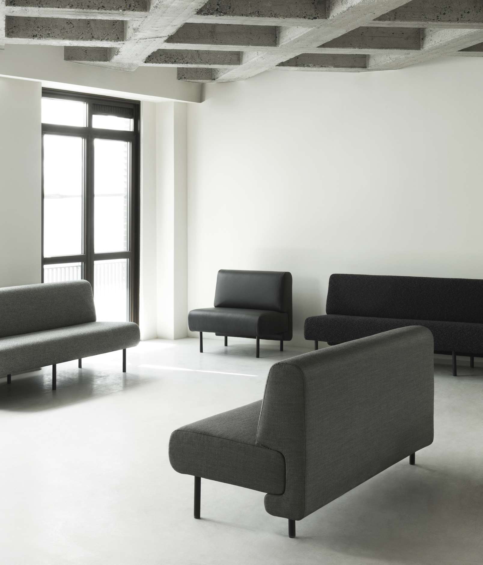 Helles Interieur mit grauen und schwarzen Sofas, darunter ein Fram Sofa von Normann Copenhagen.