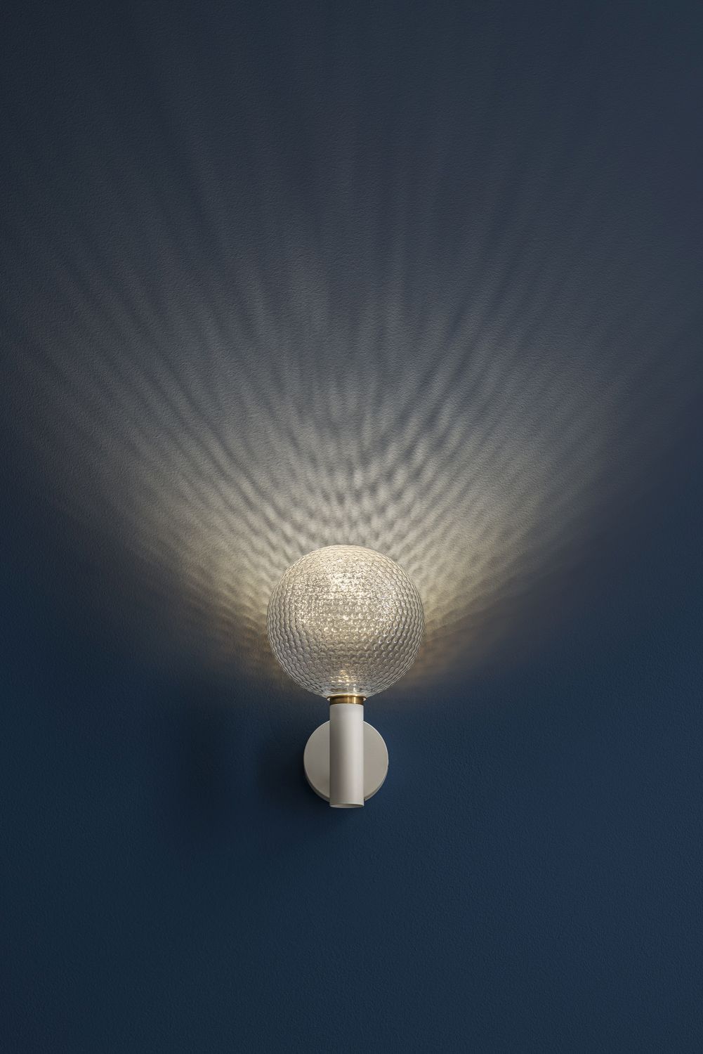 Nahaufnahme der Catellani & Smith Wandleuchte Par 18 mit dekorativem Lichteffekt an blauer Wand.