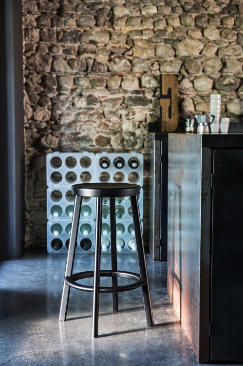 Schwarzer Déjà-vu Barstool Medium Barhocker von Magis vor einer Steinwand und einem Weinregal.