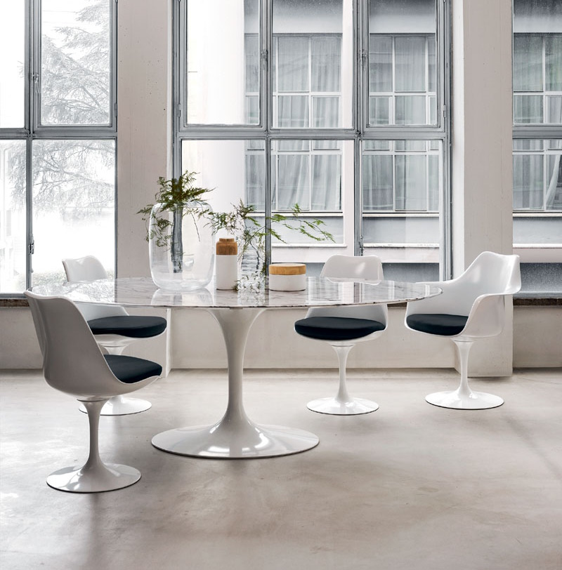 Esstisch mit Marmorplatte und weißen Tulip Stühlen mit schwarzen Sitzkissen in einem hellen Raum.