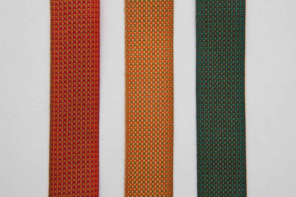 Nahaufnahme von drei Stoffstreifen in Rot, Orange und Grün für Santa & Cole Leuchten.