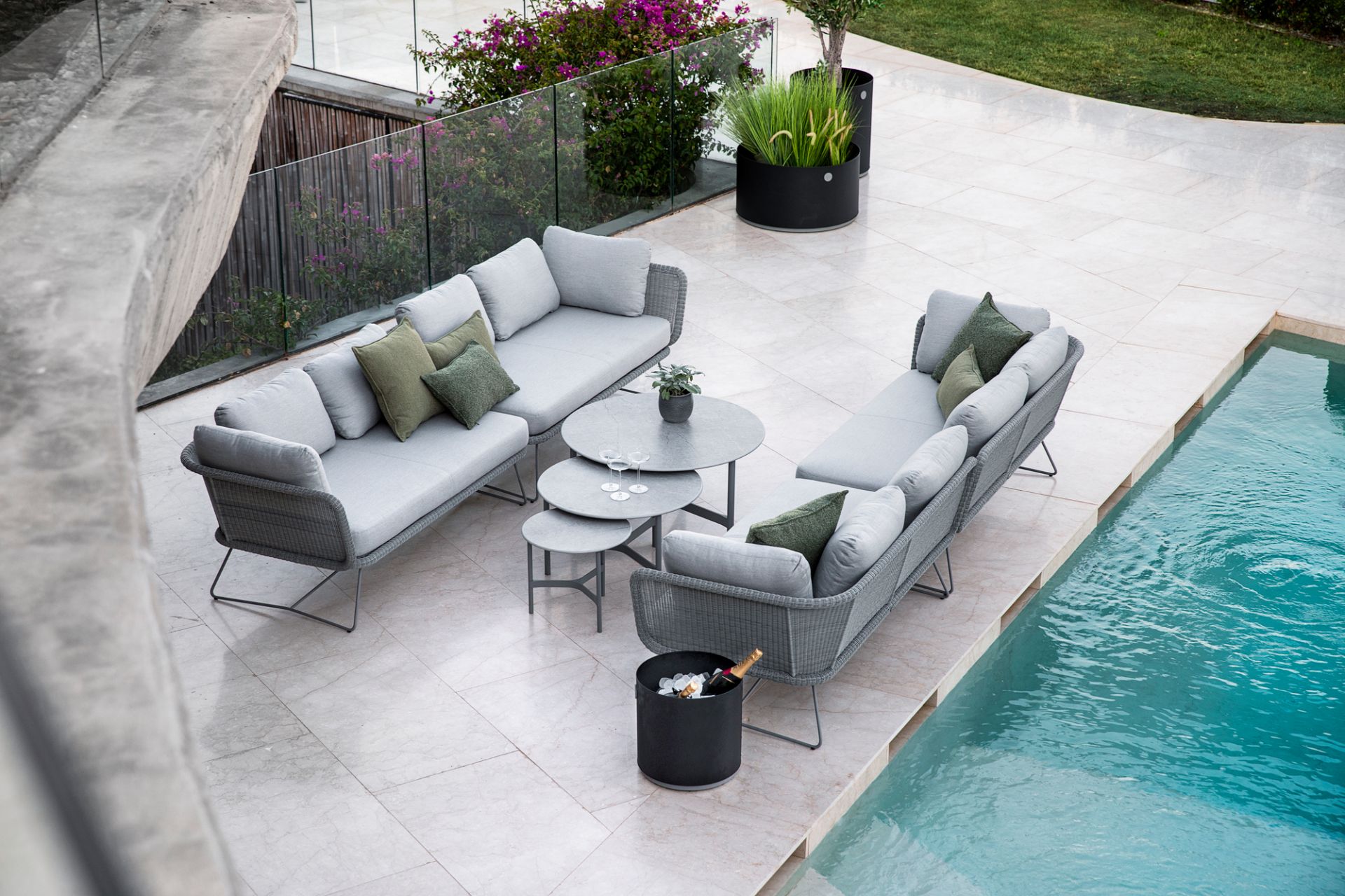 Graue Gartenmöbel-Lounge am Pool: Zwei Sofas, Couchtische und Champagnerkühler für stilvolle Outdoor-Entspannung.