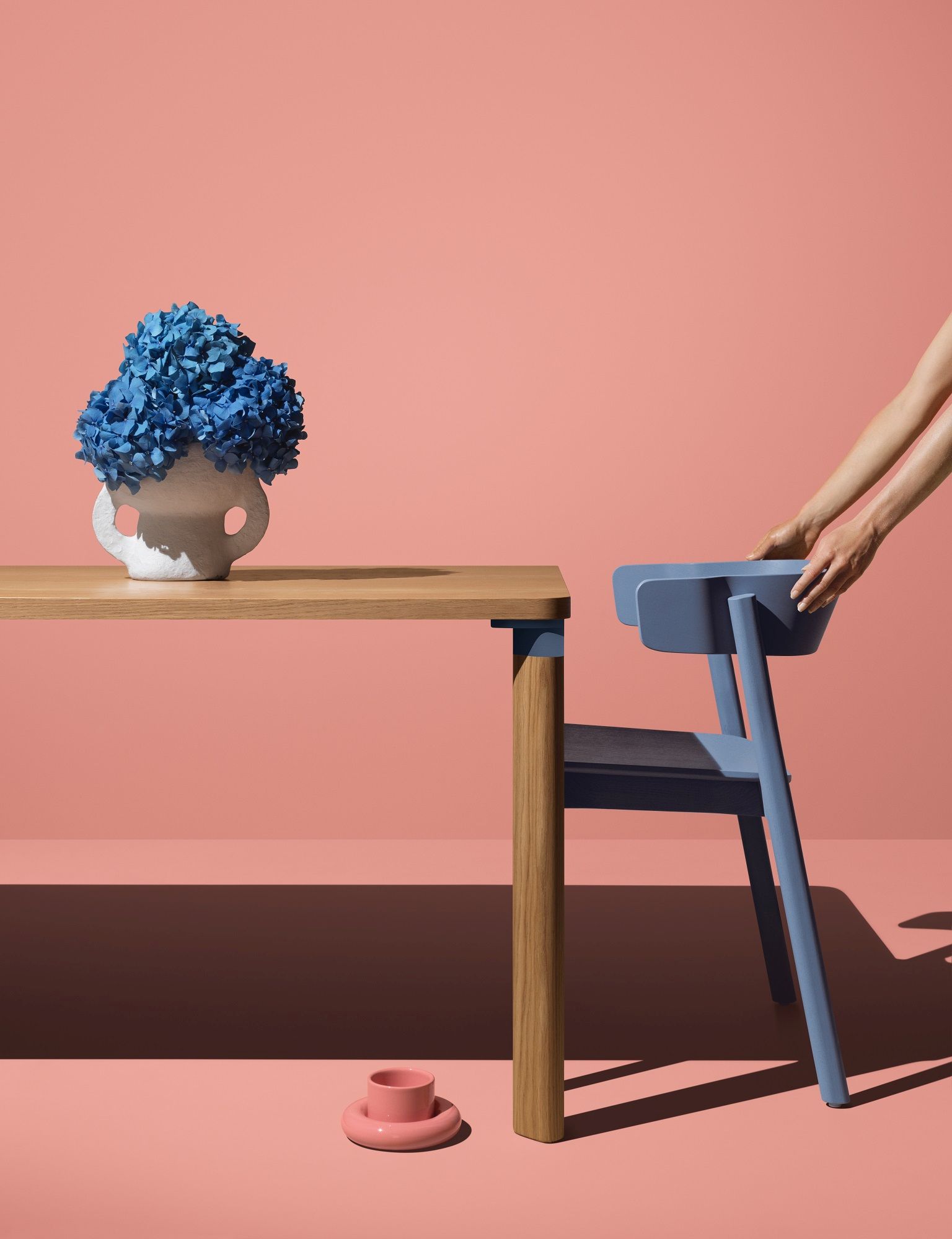 Enfold Chair Stuhl von Mizetto in Blau, neben Holztisch mit blauen Hortensien.