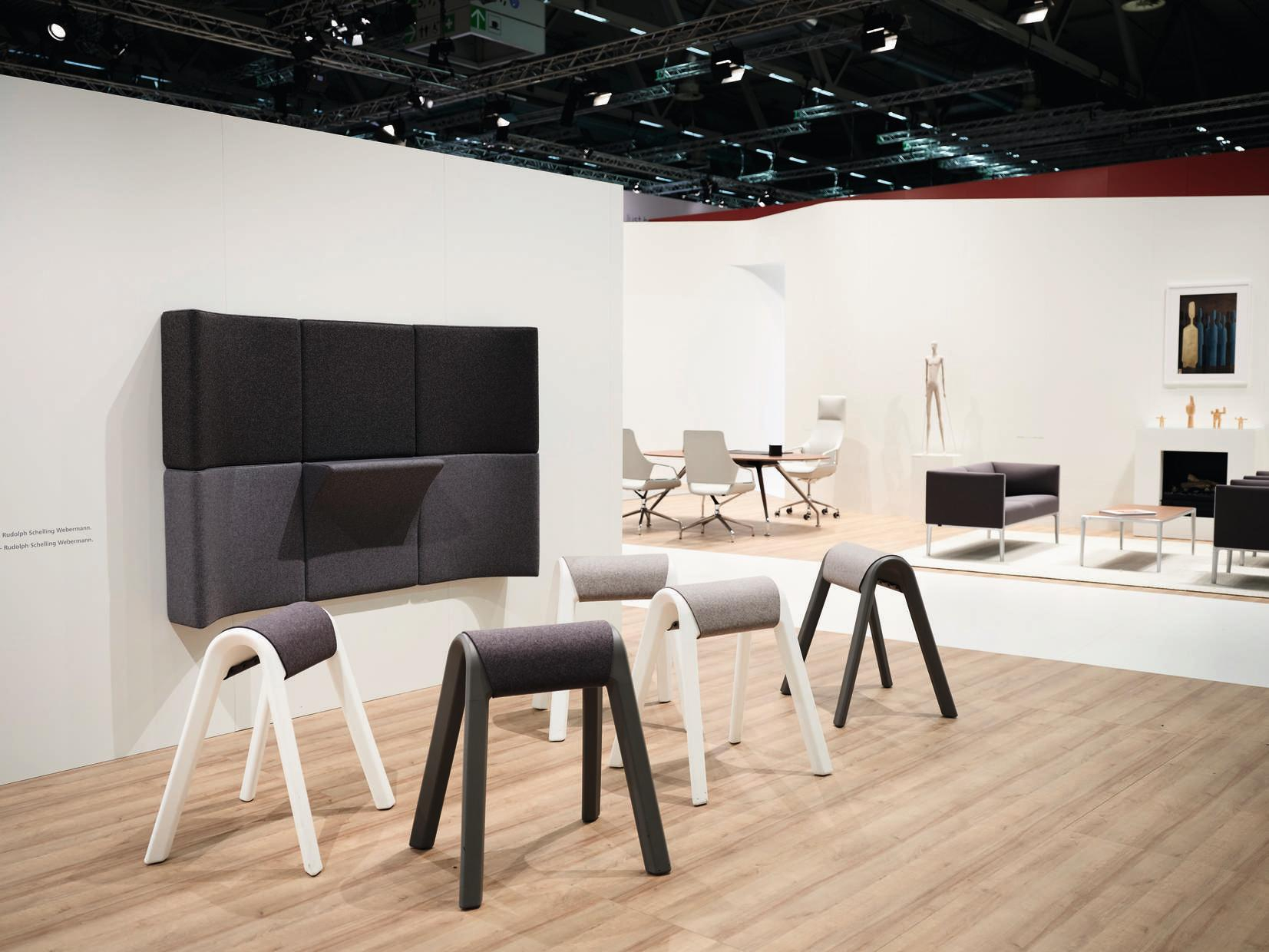 Anthrazitfarbene Sitzauflagen von Wilkhahn Programm 204 auf einer Messe, moderne Büromöbel und Designelemente im Hintergrund.