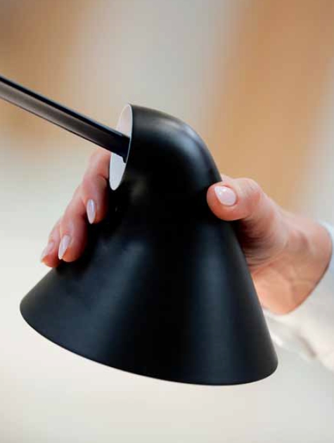 Detailaufnahme: Hand justiert schwarzen Lampenschirm der Louis Poulsen NJP Tischleuchte.