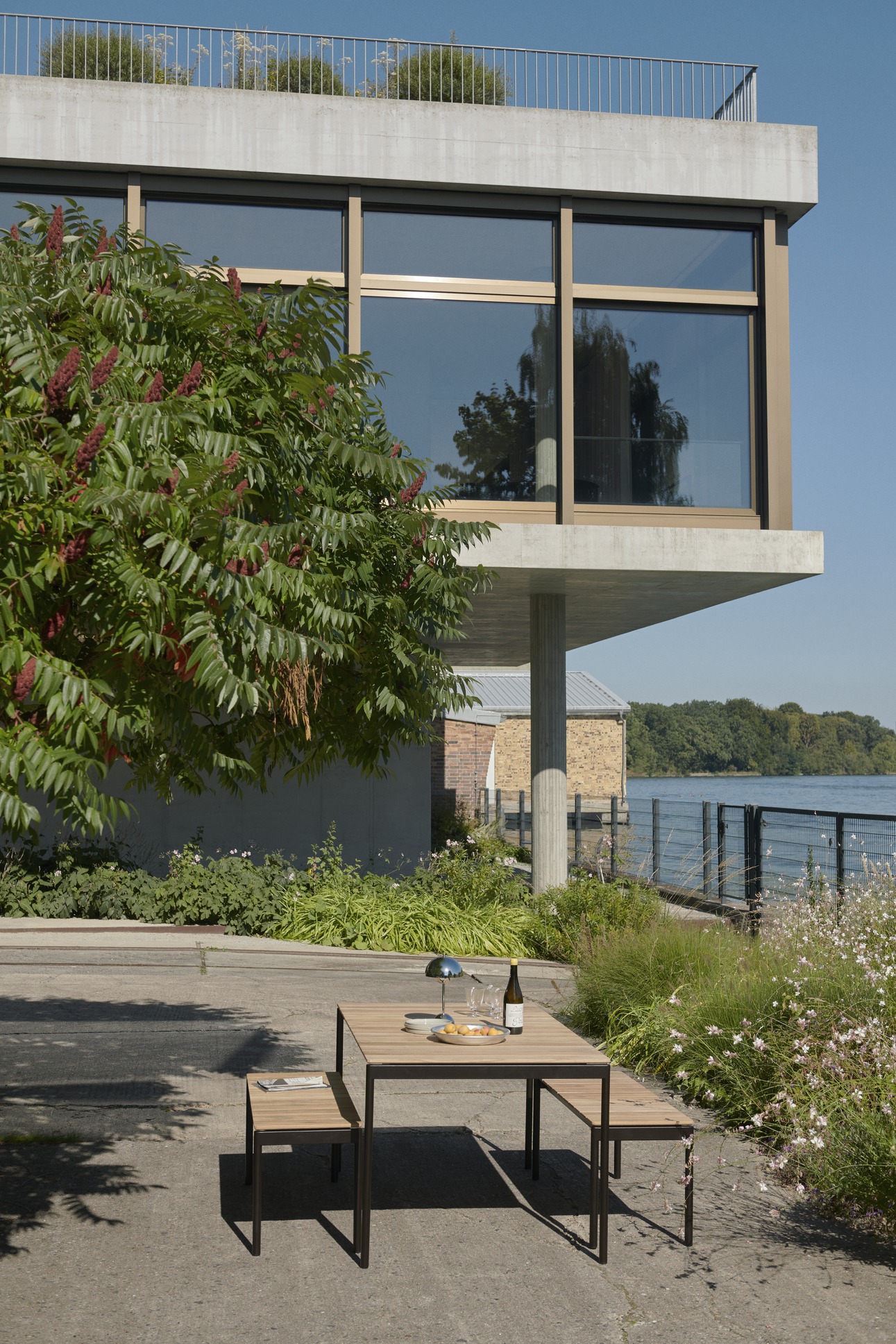 Ville AV33 Outdoor Chair von AndTradition als Teil einer Essgruppe im Freien mit Tisch und Bänken.