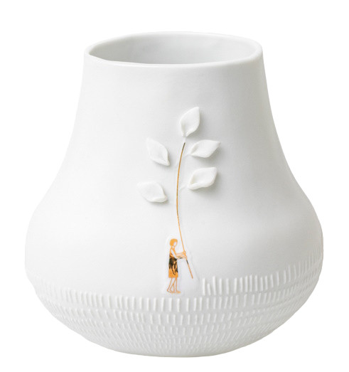 Dankbar Wiese: Nahaufnahme einer weißen Vase mit filigranem Blätterdekor und Person. Dekorative Keramik für Zuhause.