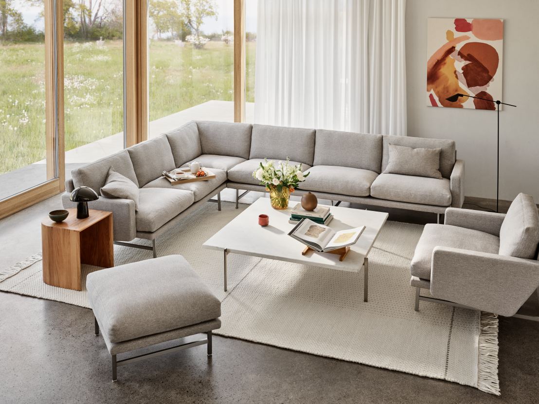 Wohnzimmer mit grauer Eckcouch, Sessel und Fritz Hansen MS Series Stehleuchte im Hintergrund.