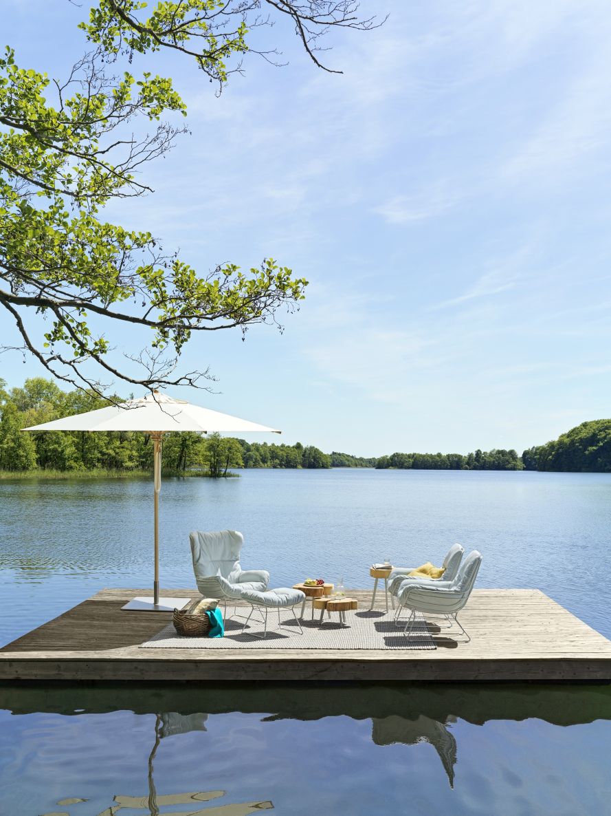 Leyasol Ottoman Outdoor von Freifrau Manufaktur auf Holzsteg am See mit Sonnenschirm.