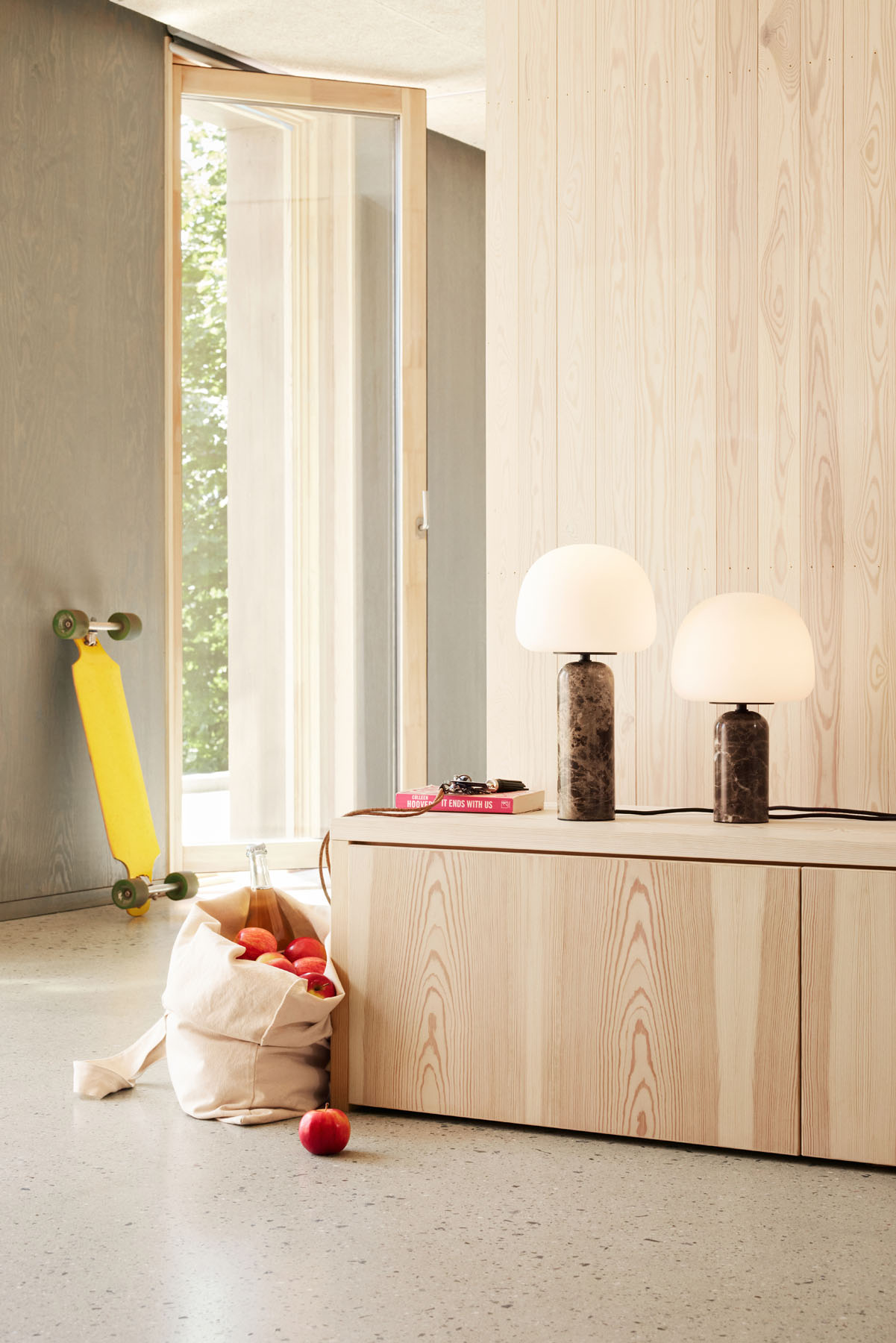 Zwei Kin Tischleuchten von Northern auf Holzkommode, modernes Wohnambiente mit Skateboard und Äpfeln.
