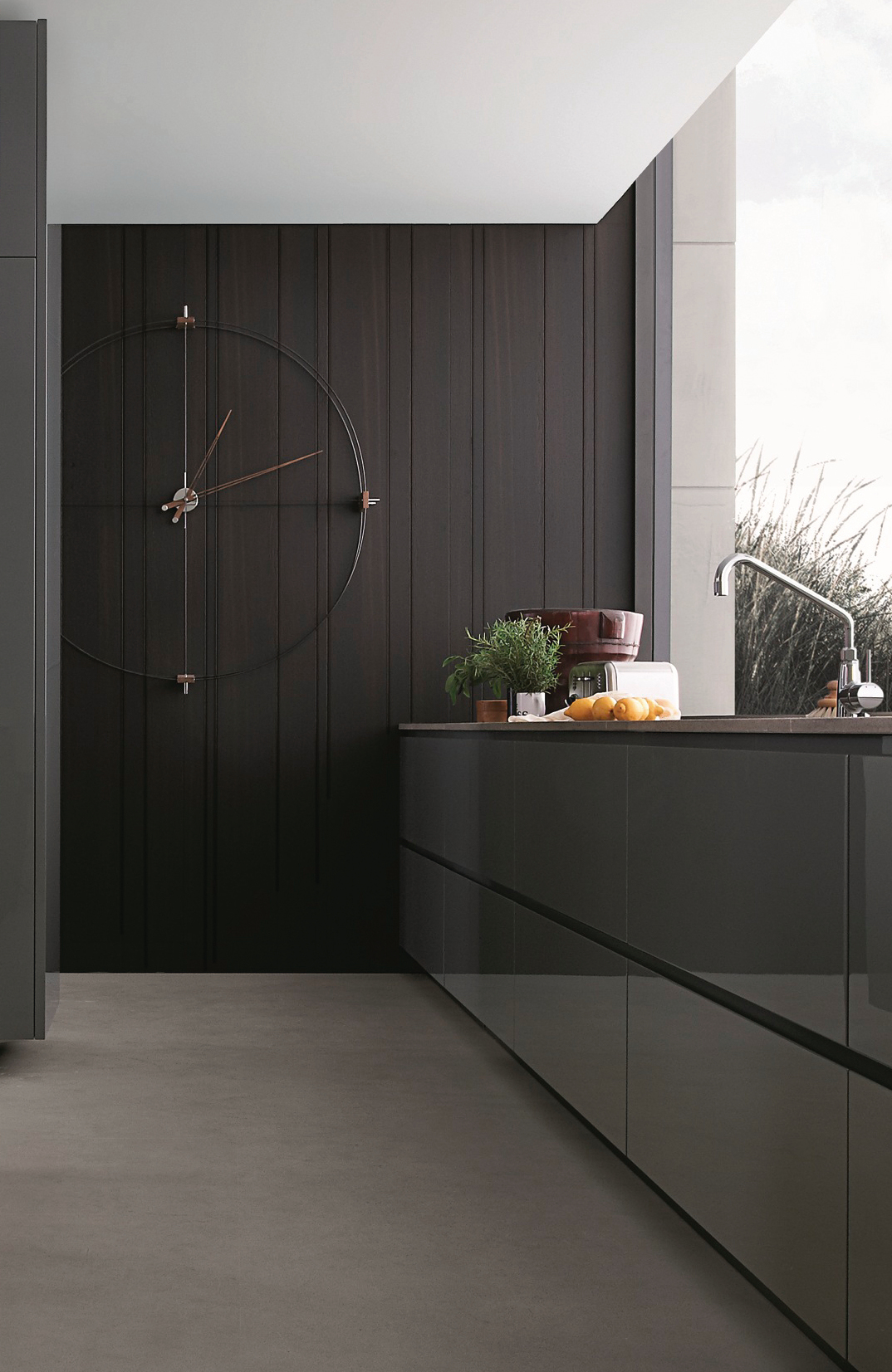 Delmori Clock Wanduhr: Moderne Wanduhr in Schwarz und Walnuss an dunkler Holzvertäfelung in Küche.