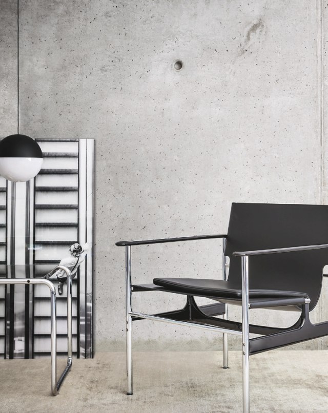 Schwarzer Pollock Sessel von Knoll International mit Chromgestell vor Betonwand. Designklassiker für stilvolles Wohnen.