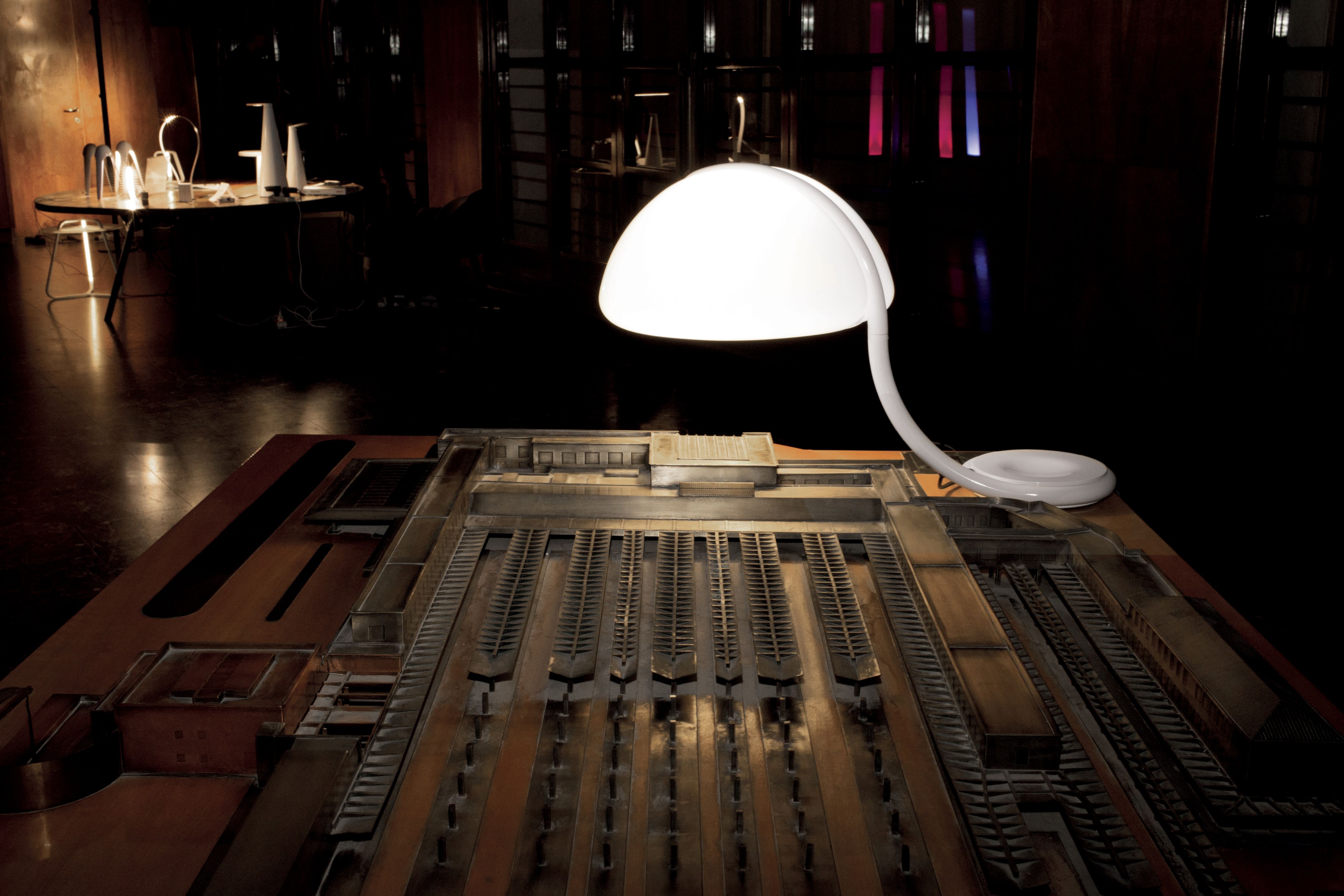 Serpente Tischleuchte von Martinelli Luce, goldfarben, auf einem Tisch mit Modellbau.