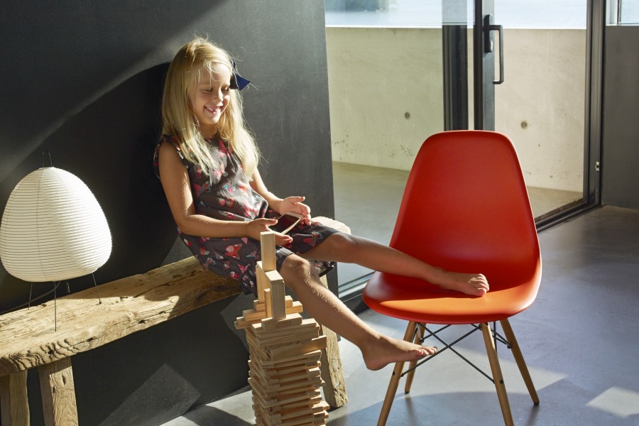 Mädchen spielt neben Akari Lampe auf Bank und rotem Stuhl. Japanische Designleuchte.