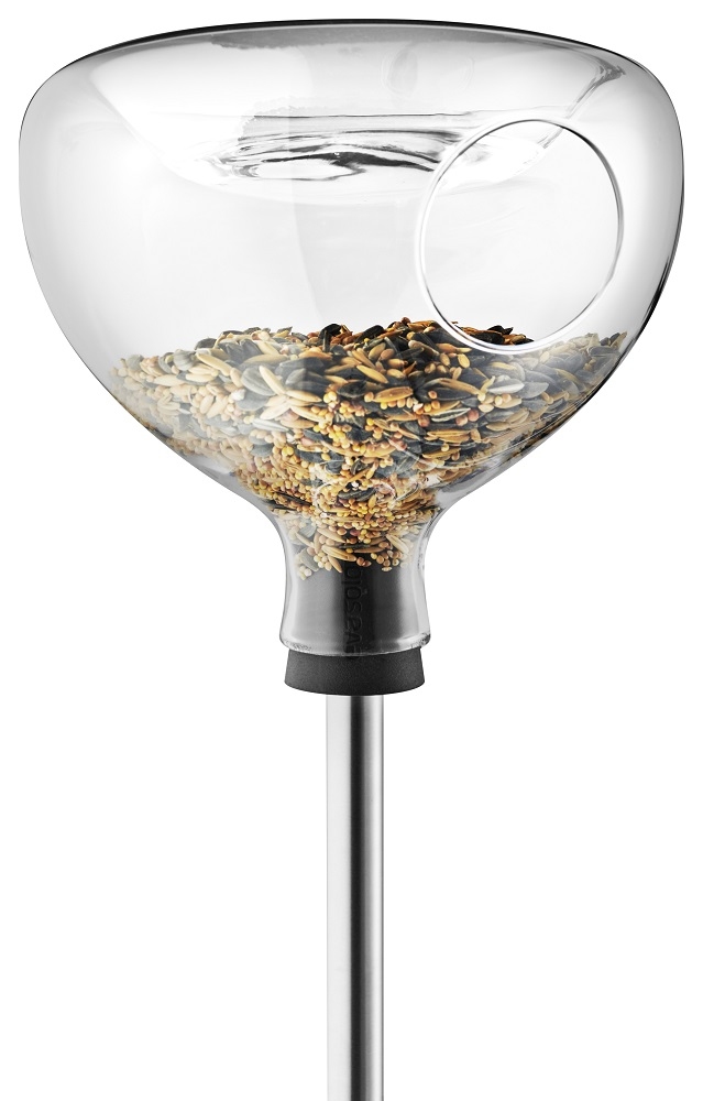 Glasfutterhaus mit Vogelbad von Eva Solo, gefüllt mit Vogelfutter auf einem Edelstahlstab.