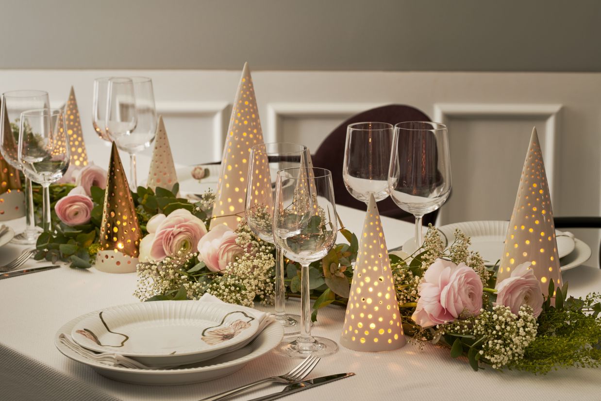 Festliche Tischdekoration mit Kähler Nobili Teelichthaltern in Schneeweiß und Gold, umgeben von Blumen.