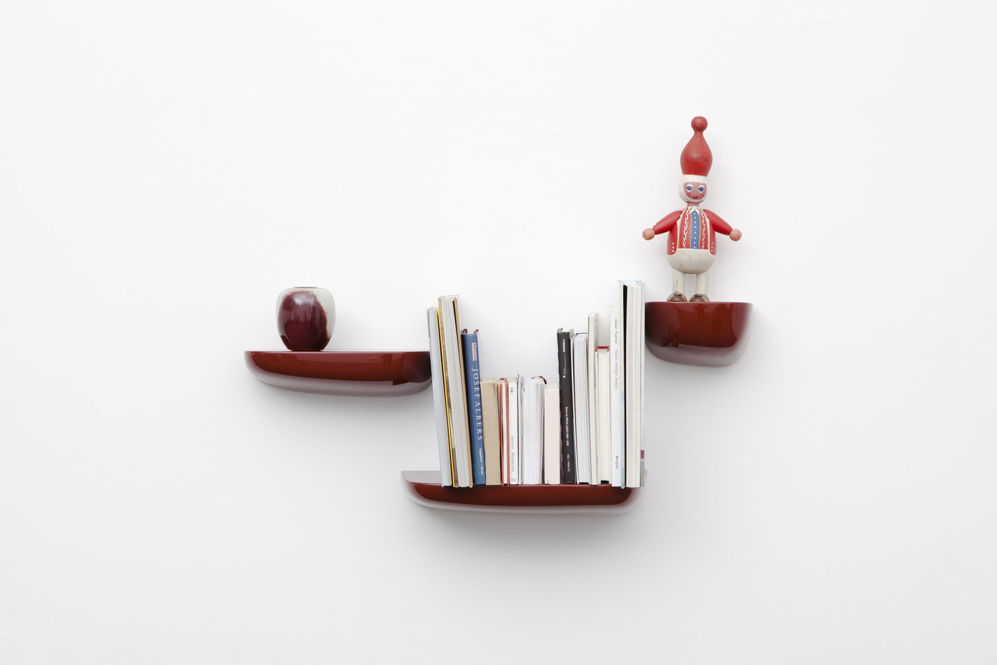 Drei rote Vitra Corniches Wandboards mit Dekoration an einer weißen Wand.