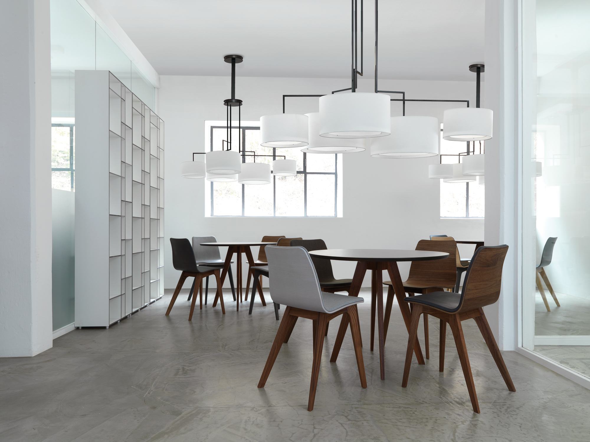 Helles Büro mit mehreren Tischen und Stühlen, im Hintergrund ein Code 1 Holzregal.