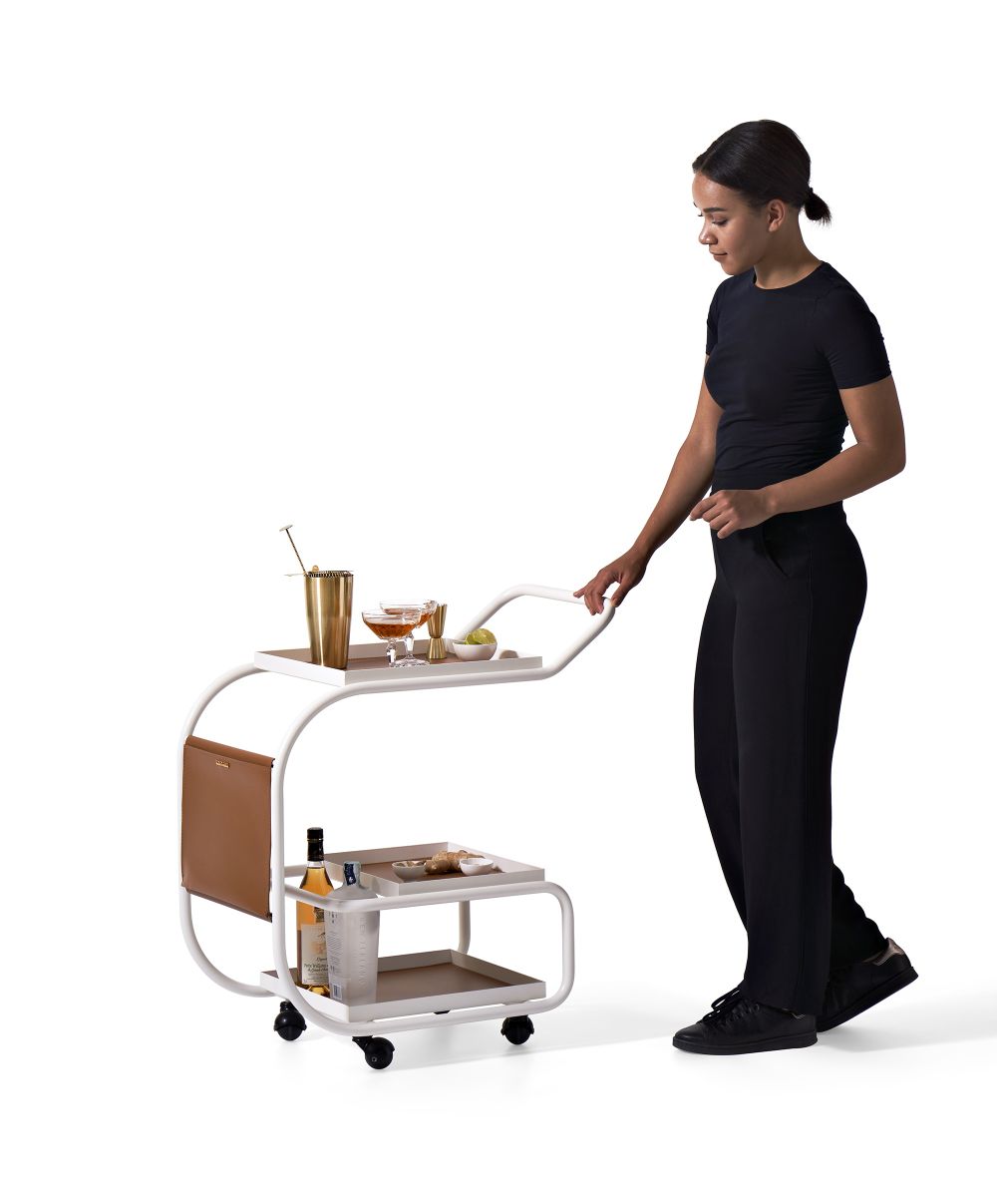 Frau schiebt weißen Zenzero Servierwagen von Opinion Ciatti mit Getränken und Spirituosen.