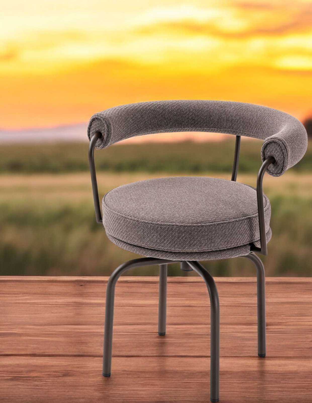 Grauer Cassina 7 Fauteuil Tournant Drehsessel für den Außenbereich auf Holzterrasse mit Sonnenuntergang im Hintergrund.
