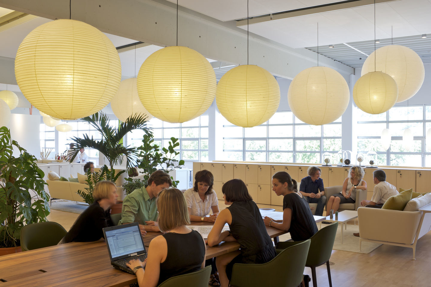 Innenraum mit mehreren Akari Pendelleuchten von Vitra, die über einem Konferenztisch hängen.